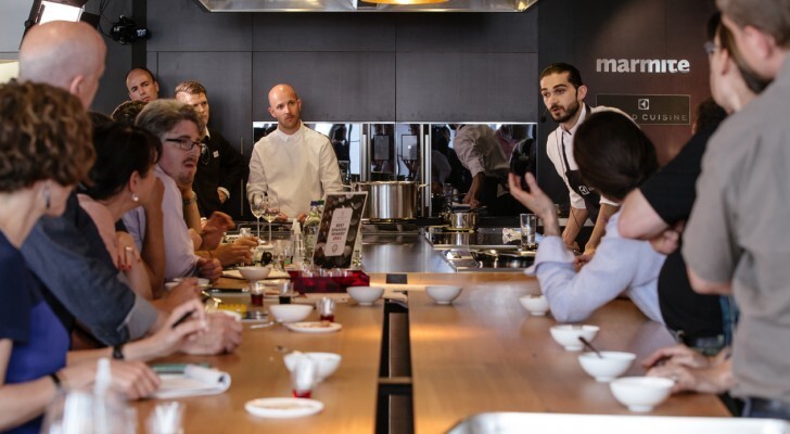 Jozef discussing food with participants seated around a working kitchen table